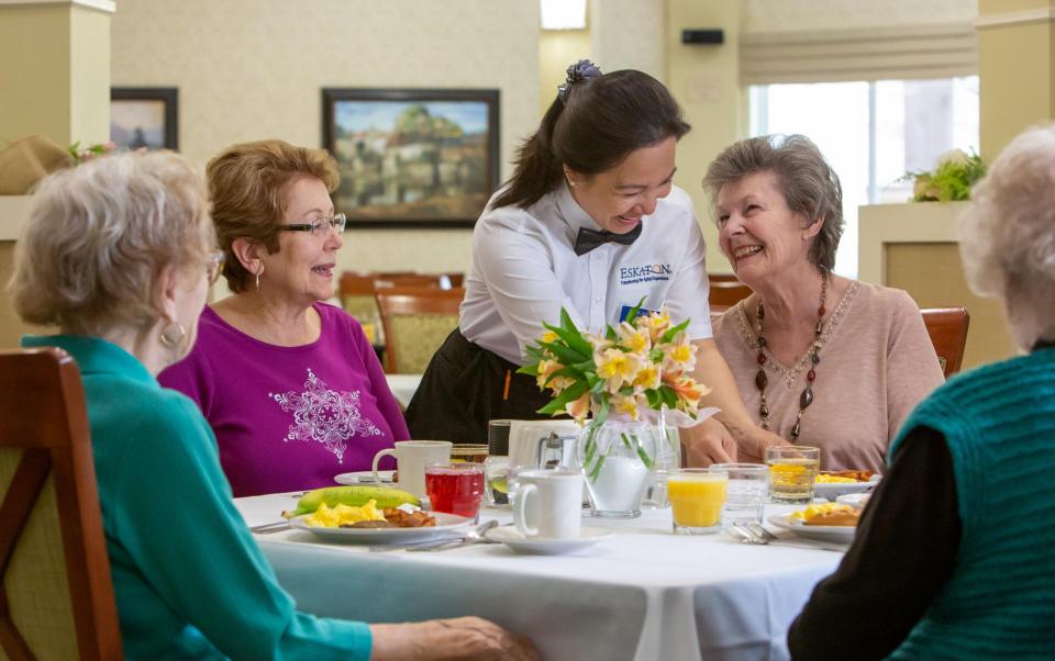 Residents dining and laughing with staff