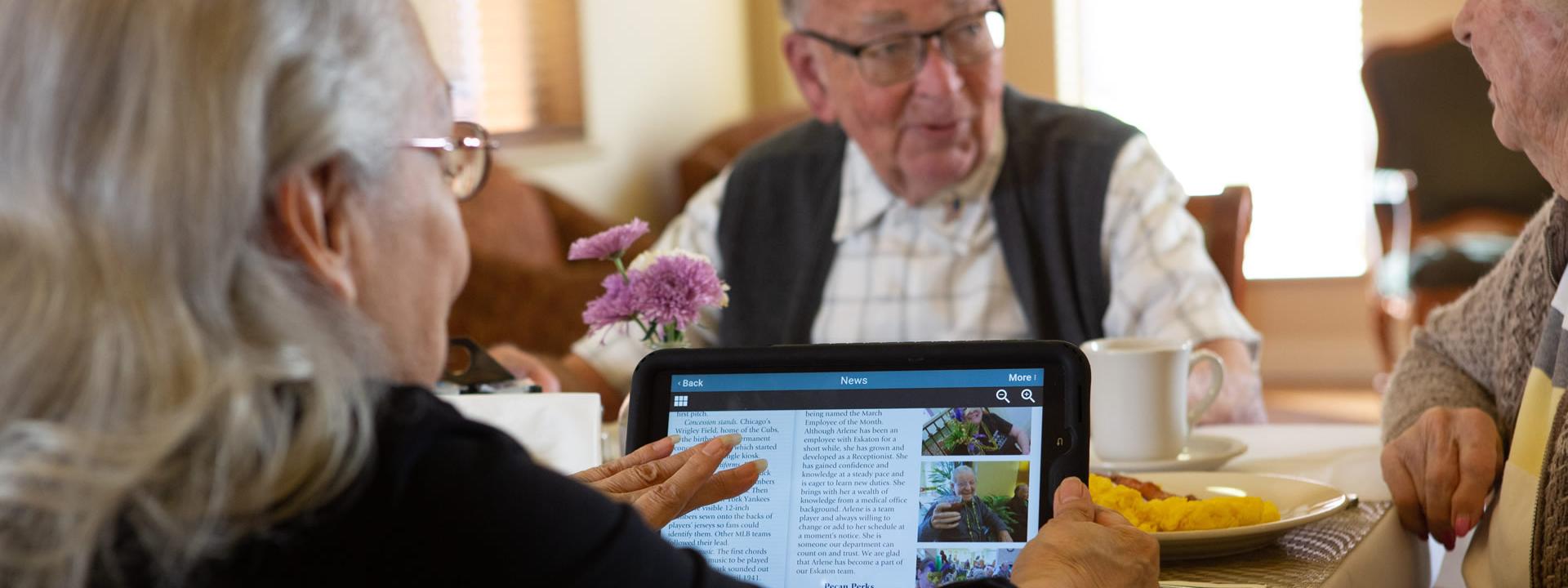 Three resident having breakfast and reading the news.