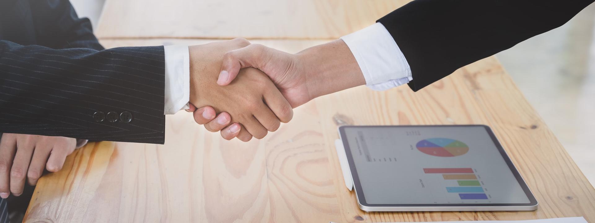 Hand shake with computer on the table