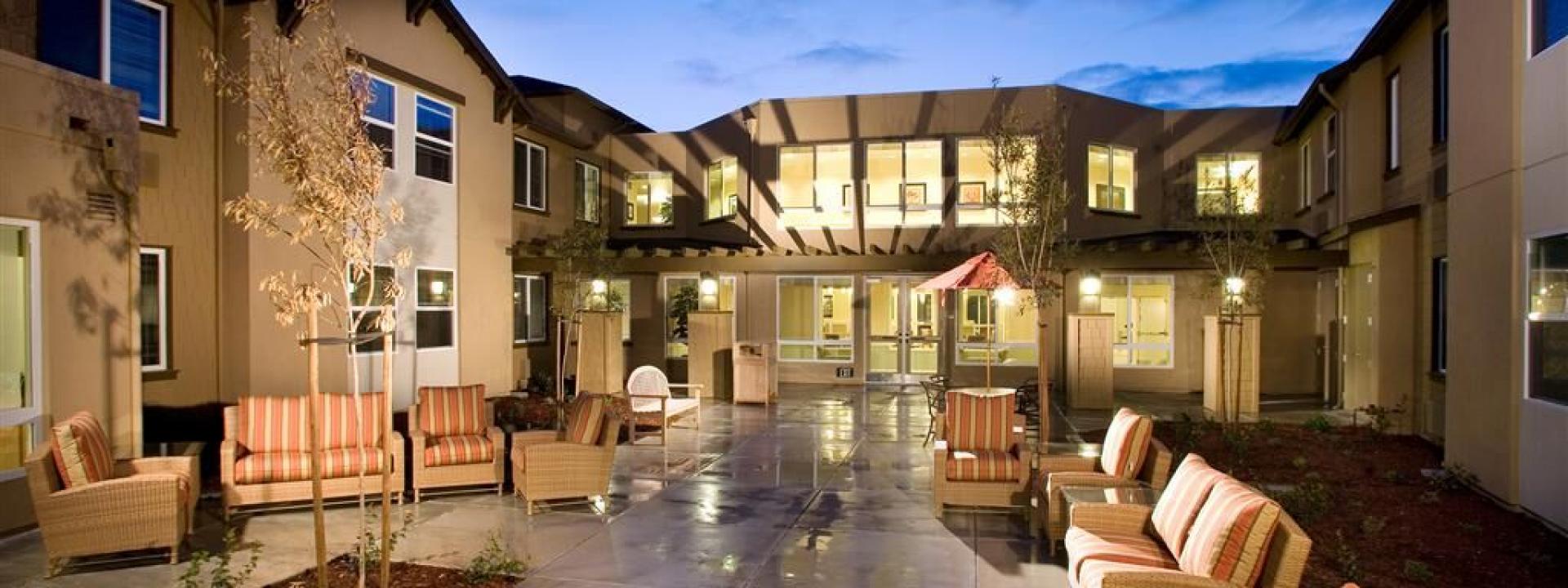 The Parkview patio area with lounge chairs, table, chairs and umbrella, and trees