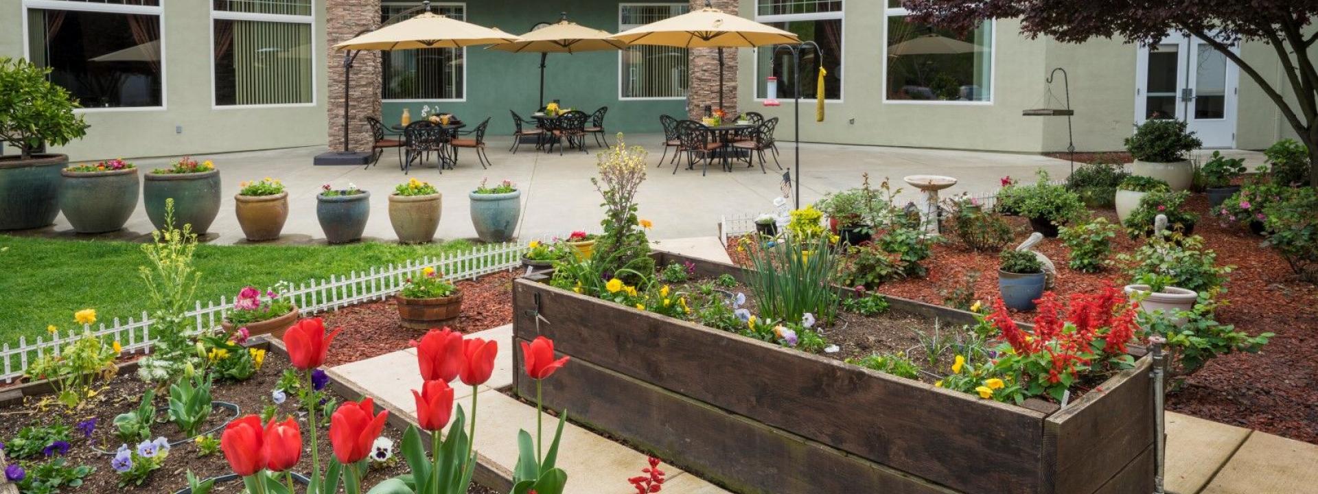 Outdoor patio with round table, chair, umbrellas, flower garden and potted plants