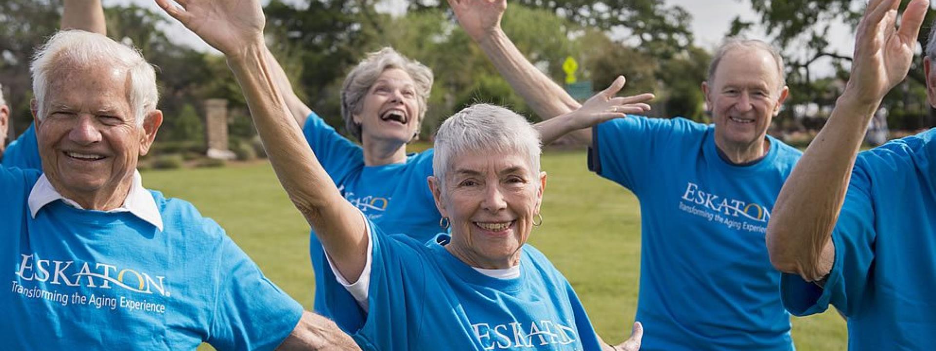 A group of residents wearing their blue Eskaton t-shirts exercising outside on the lawn