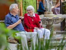Couple sitting by water fountain enjoying a glass of red wine.