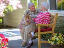 Two women sitting outside on a bench talking.