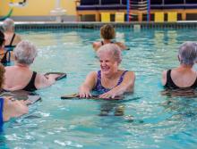 Several residents in the indoor pool enjoying a water aerobics class