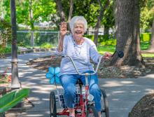 Resident riding her bike, smiling and waving