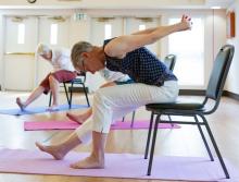 Two women sitting a chairs doing stretch exercises