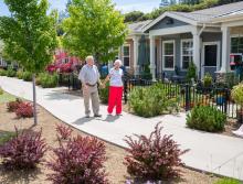 A smiling couple holding hands,  walking along the patio homes walking path