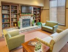 Lobby area with couch, love-seat, chair, fireplace and a entertainment center with books and TV