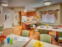 Activity room with tables and chairs and a  small kitchen area.