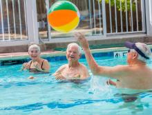 Residents in the in-door swimming pool tossing a beach ball to each other.