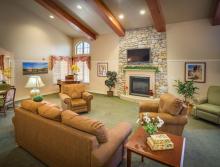 Community living room with a couch, three comfy chairs and a fireplace.