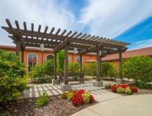 Patio area with a Gazebo and bench surrounded by beautiful plants.