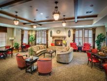 Village Center's community room with couches, chairs game tables and fireplace.