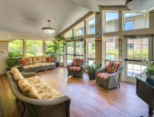 Common social area with couches, chair, piano and plants.