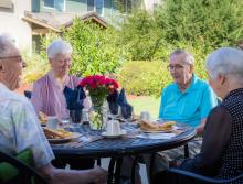 Four residents sitting around the outside patio table socializing