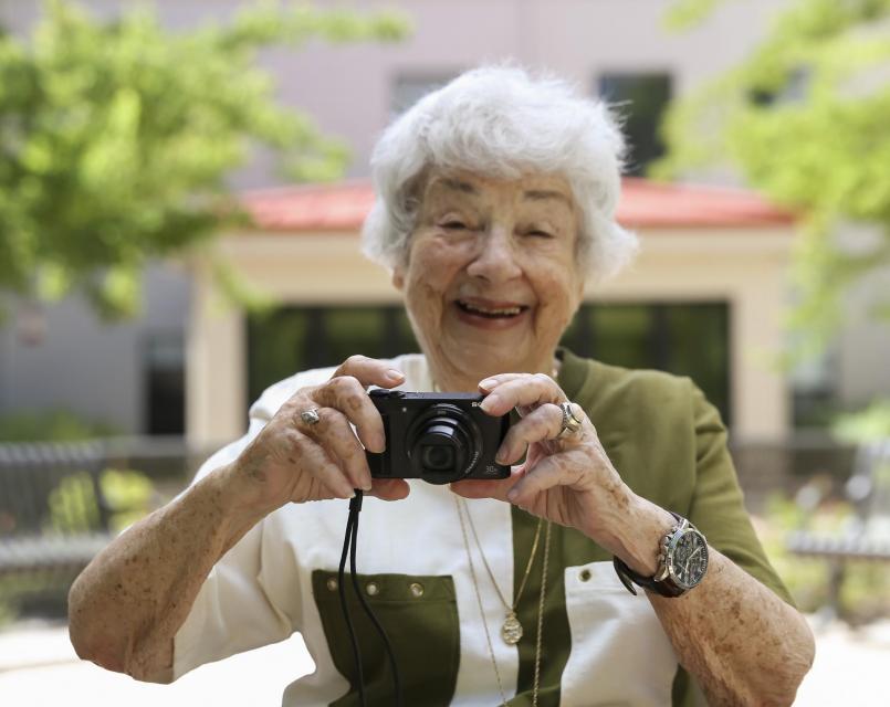 Resident Gloria Ruth smiling with her camera in-hand