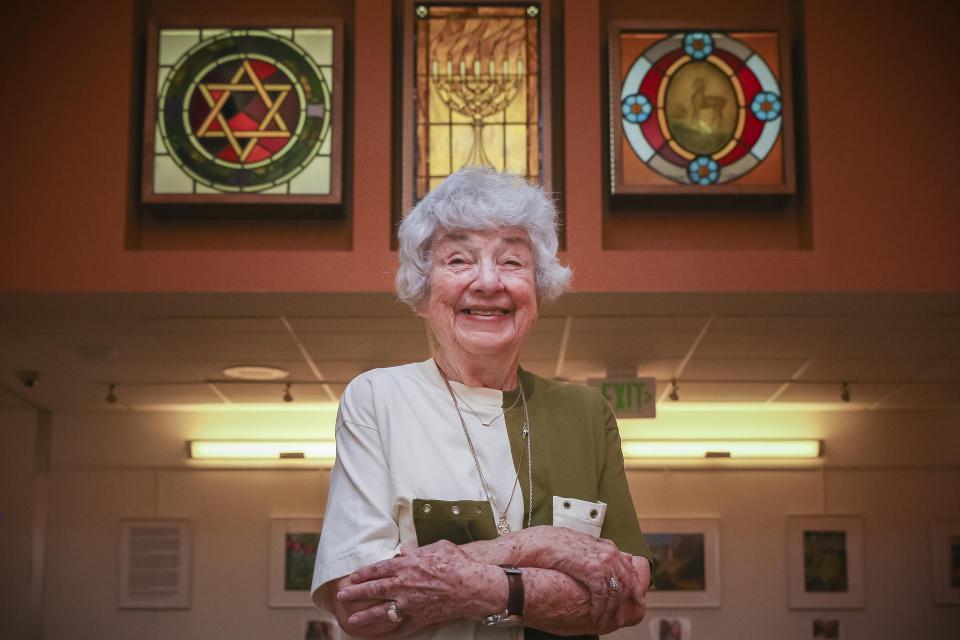 Gloria, smiling and standing below the beautiful Jewish symbols