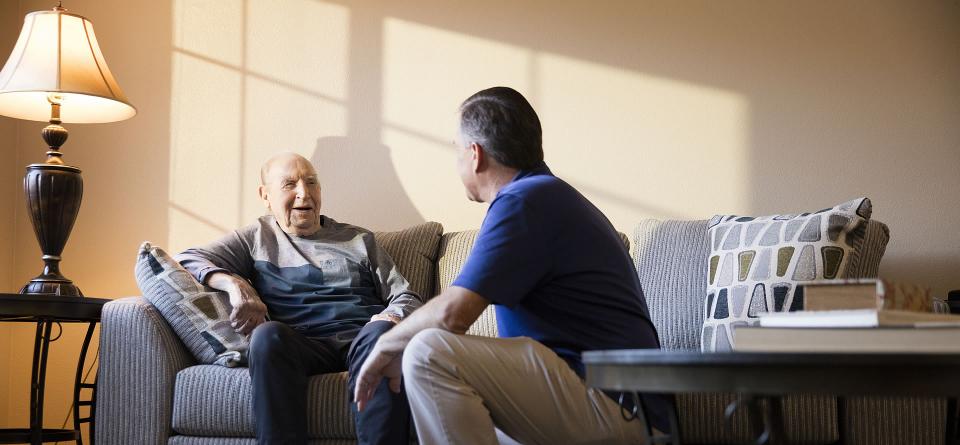 Caregiver and resident sitting a the couch smiling and talking