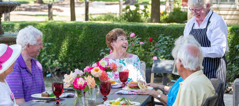 Residents laughing and enjoying lunch on the patio