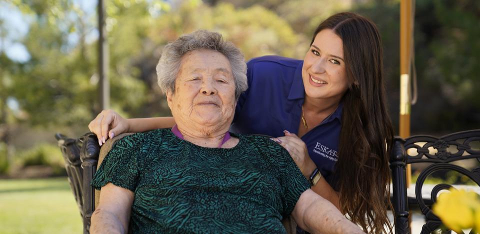 Woman sitting outside on the patio with smiling staff behind her