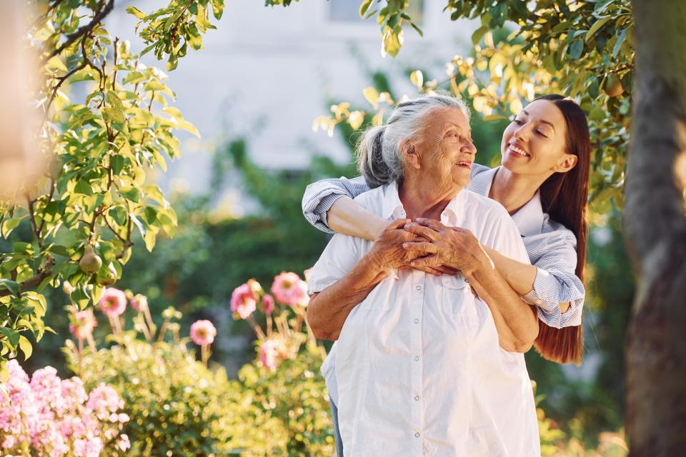 Staff smiling with her arms around a woman resident