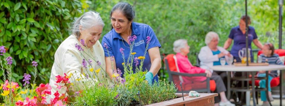 Resident and staff planting in a raised planter box