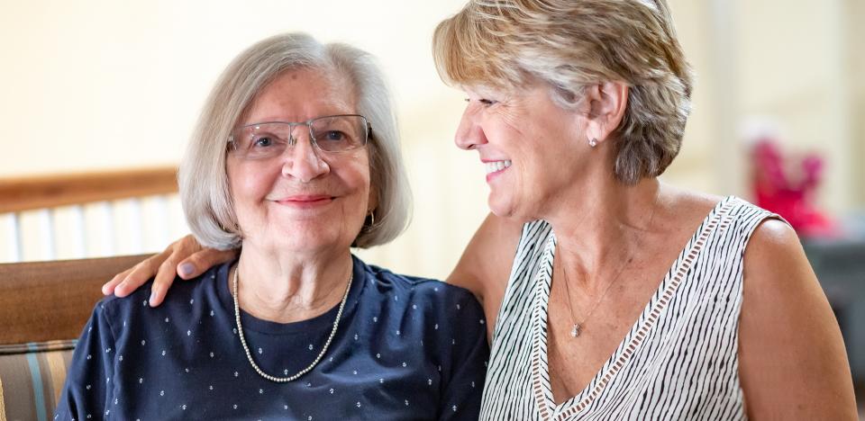 Mother and daughter smiling with arms around each other