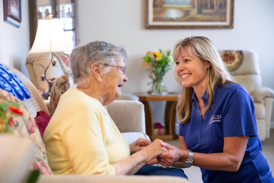 A women caregivers smiling and holding hands of a woman resident.