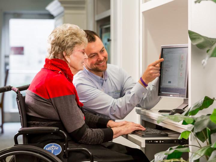 Staff teaching resident how to use the computer and some programs.