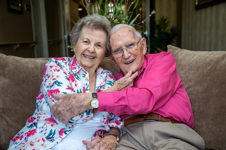 Mr. and Mrs. Mills' sitting on a couch smiling and hugging each other.