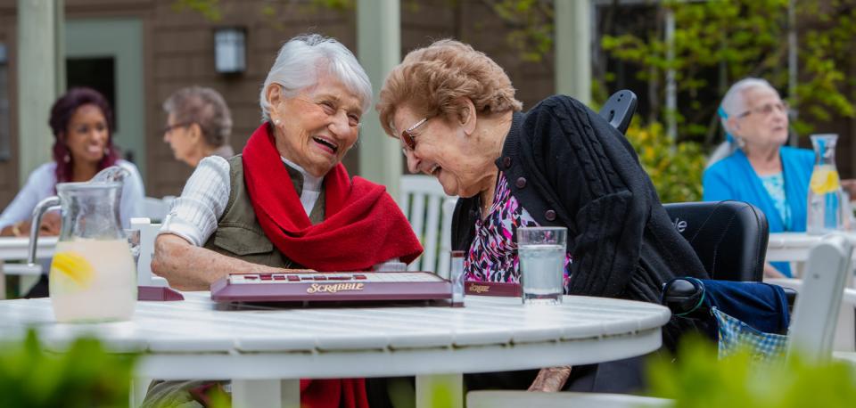 Residents on patio, playing a game of Scrabble and laughing