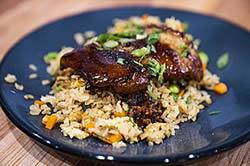 A blue dinner plate with Teriyaki chicken, California fried rice