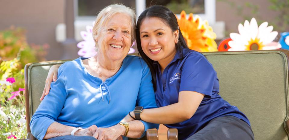 Staff with her arms around a resident, both smiling