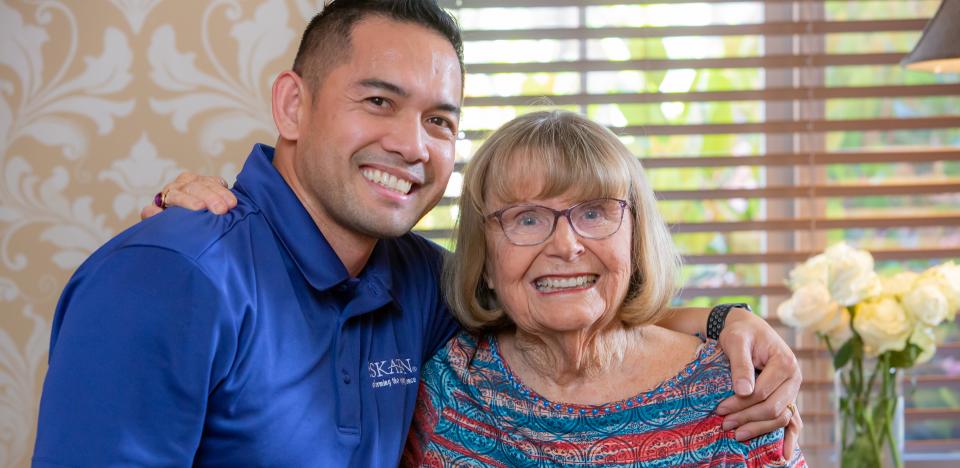 Woman resident and male staff smiling with arms around each other