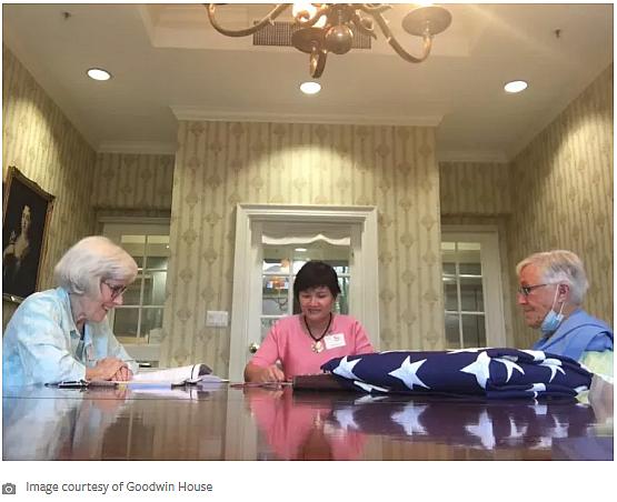 Three women sitting around a table with a folded American flag
