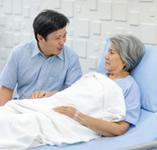 Family member visiting woman in hospital bed