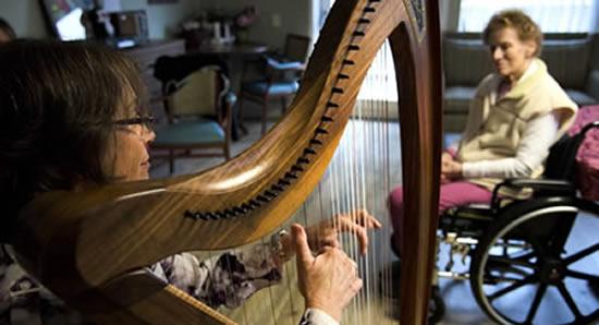 A woman harpist play music for a woman resident in a wheelchair