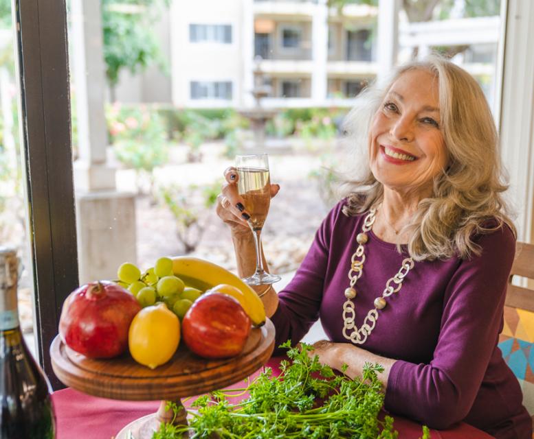 A smiling resident, cheering with a glass of wine.