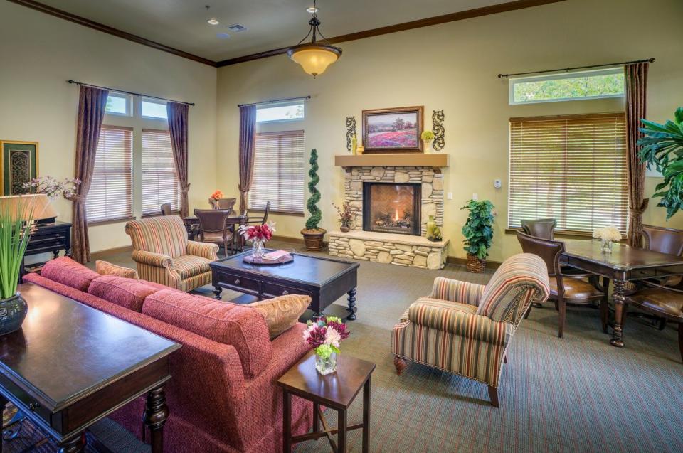Community living room with a fireplace, couch, two comfy chairs, and a table with four chairs