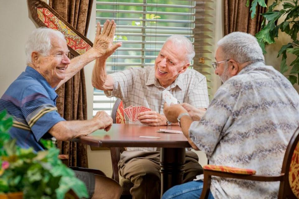 Three men playing a game of cards; two giving each other a high five..