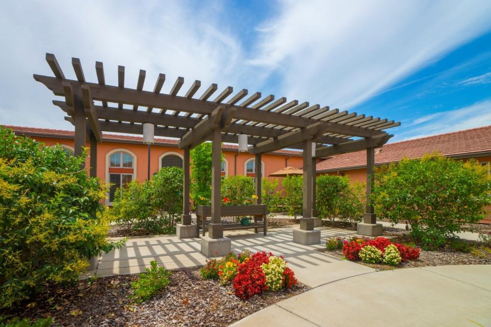 Patio area with a Gazebo and bench surrounded by beautiful plants.