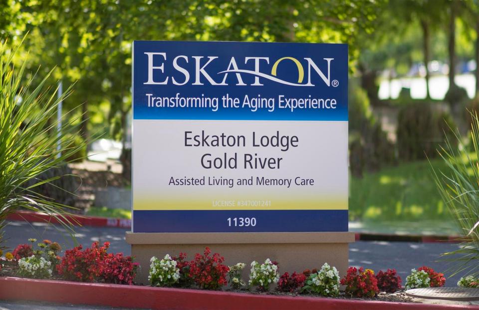 Eskaton Lodge Gold River sign with red and white flower planted below it.
