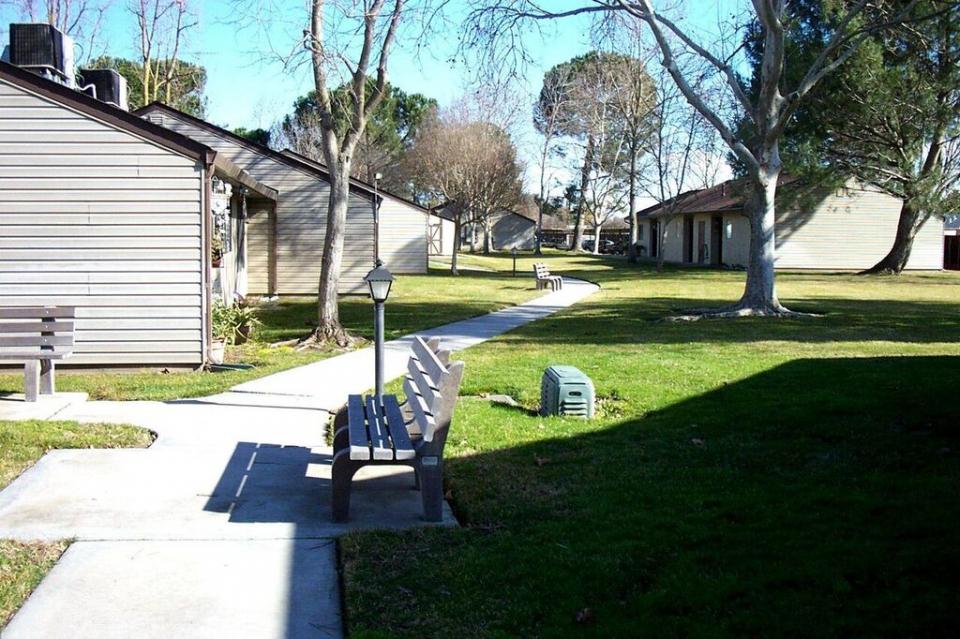 Exterior of Eskaton Manteca Manor's apartments with benches, trees and green lawns.