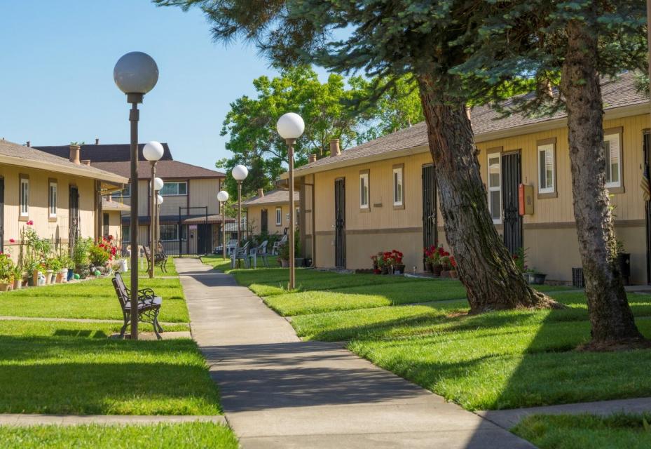 Exterior of Eskaton Hayfork Wilson's apartments with green trees and lawns, benches and flowers.