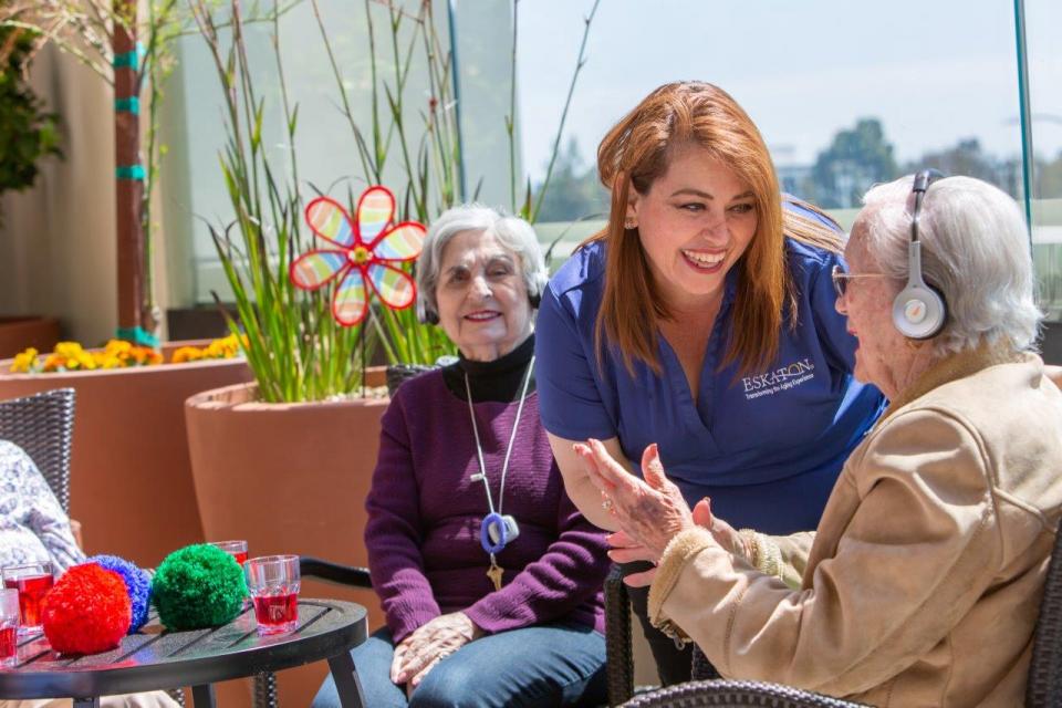 Smiling staff and residents listing to music with headsets
