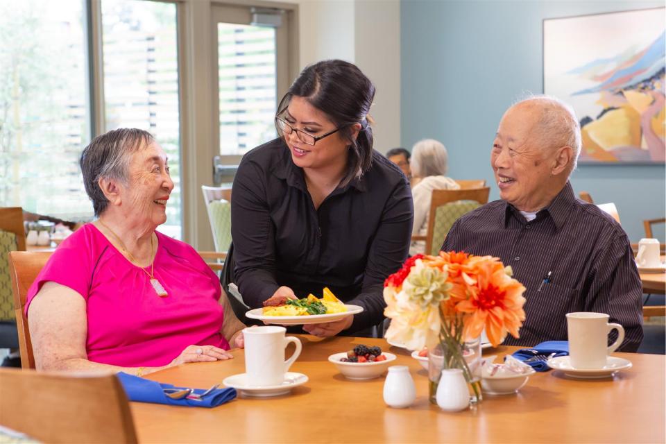 Smiling couple being served lunch in dining room