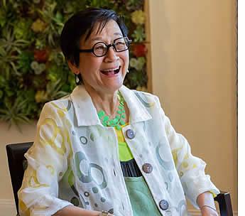 A woman resident sitting on a chair, smiling.