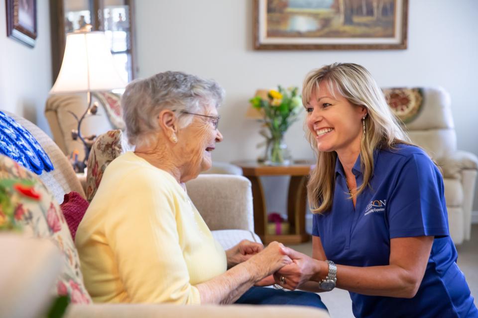 A women caregivers smiling and holding hands of a woman resident. 