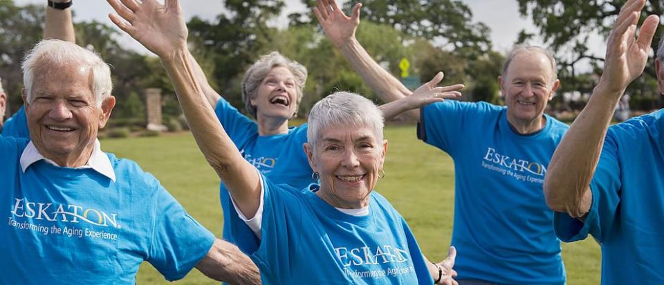 A group of residents wearing their blue Eskaton t-shirts exercising outside on the lawn